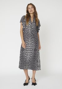 Rochie cu imprimeu leopard în alb și negru, având mâneci fluture, croi lejer și o lungime medie. Asortată cu pantofi cu toc din satin negru.