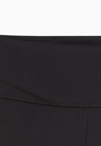 Sorte højtsiddende leggings lavet af strækbart stof. Har en flad talje og flade sømme for en glat afslutning. Ingen yderligere mønstre.