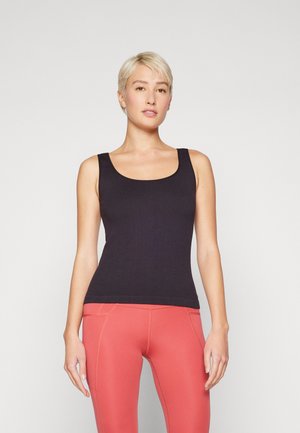 Svart ribbestrikket tanktop med dyp utringning og brede stropper, sammen med tettsittende korallfargede leggings med kontrastsøm.