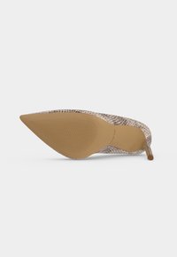 Chaussure à talon stiletto à bout pointu avec semelle beige texturée et tige à motif peau de serpent marron clair, vue du côté de la semelle.