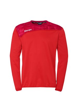 T-shirt de sport rouge à manches longues avec empiècement à motif géométrique en rouge foncé et blanc, logo "Kempa" sur l'épaule gauche.