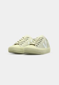 Sneakers in tela beige chiaro con logo bianco. Presentano punta rotonda, suola intermedia testurizzata e occhielli metallici per i lacci. Design a profilo basso.