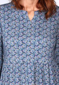Blumendruckkleid mit rundem Ausschnitt, langen Ärmeln und einem ausgestellten Saum. Der Stoff ist überwiegend blau mit rosa und gelben Akzenten.