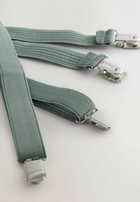 Tirantes de espiga verde hechos de material elástico con clips metálicos en ambos extremos. Presenta una tela texturizada y tejida, así como herrajes resistentes.
