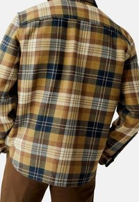 Bruin-gele geruite blousejack met een zachte textuur, voorzien van marineblauwe en witte accenten, een klassieke kraag en een rechte zoom.