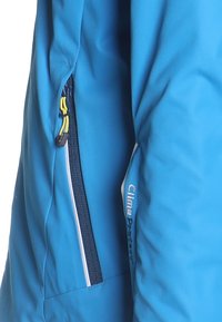 Ärmel einer blauen Jacke mit einer vertikalen Reißverschlusstasche, die gelbe Zipper-Ziehstücke und die Aufschrift "Clima Protect" in Weiß und Schwarz aufweist.