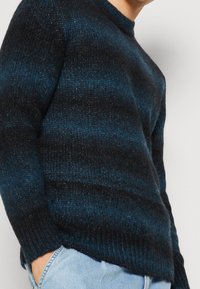 Maglione lavorato a maglia con un motivo a righe blu scuro e nere, colletto rotondo e polsini a coste. Texture morbida e vestibilità comoda.