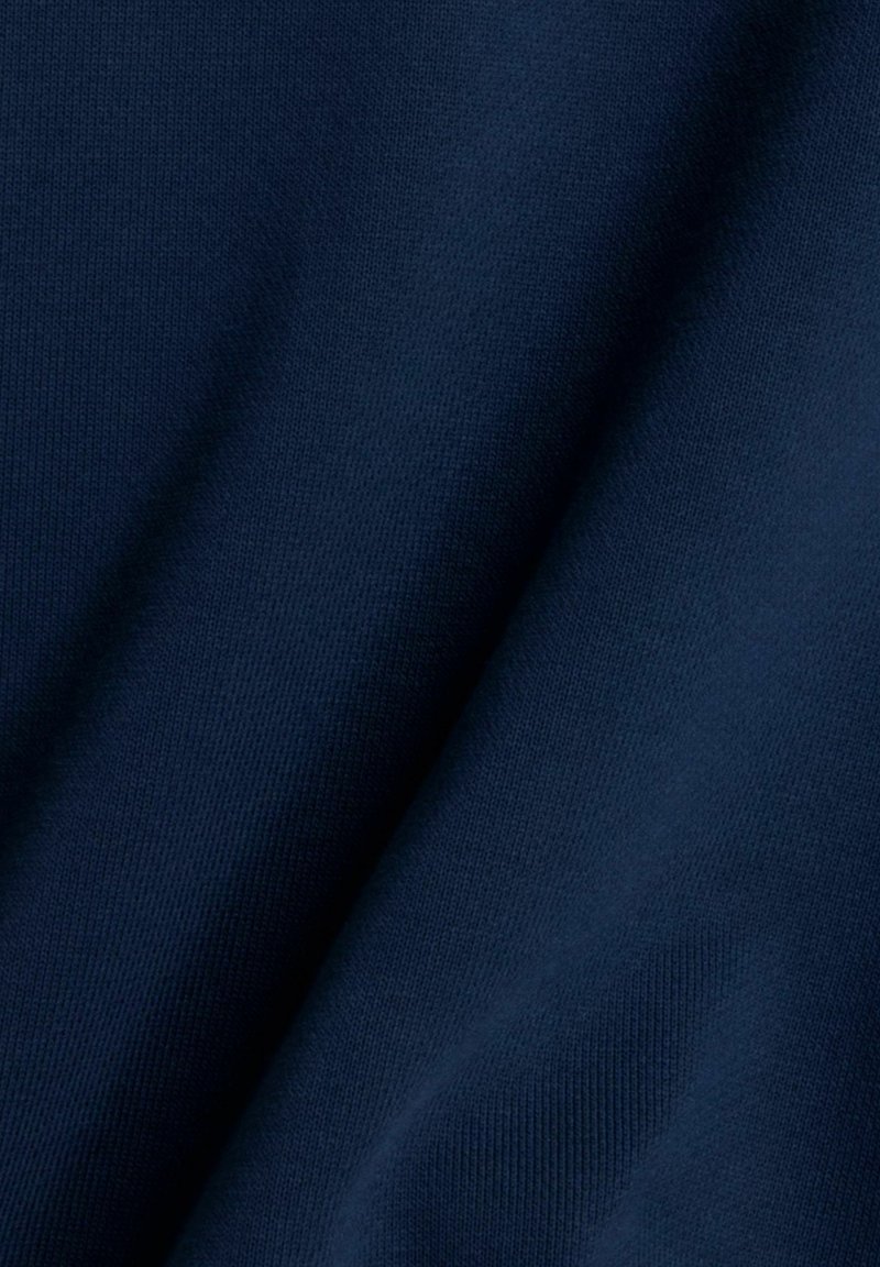 Donkerblauwe stof met een gladde textuur, met een subtiel breipatroon en zachte plooien, waarmee de zachtheid en flexibiliteit worden benadrukt.