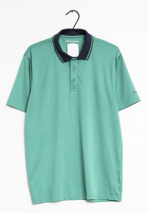Camiseta polo verde de manga corta con un sutil patrón de cuadrícula, cuello azul marino con rayas, tres botones, colgada en una percha negra, etiqueta de Pierre Cardin visible.