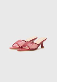 Red translucent heeled sandals featuring a crisscross strap design, pointed toe, and a mid-height heel with a smooth finish.