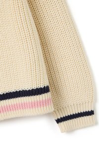 Manche d'un pull en maille couleur crème avec un motif texturé et des accents rayés en bleu marine et rose clair au niveau des poignets.