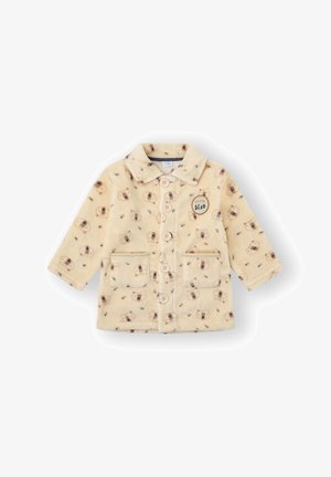 Chaqueta de felpa color crema con patrón de osos, cierre de botones, dos bolsillos delanteros y un parche redondo de "osito" en el lado izquierdo. Textura suave.