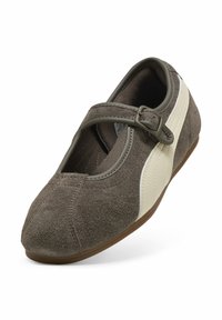 Chaussure Mary Jane en daim marron avec bande blanche sur le côté, bout arrondi et boucle réglable sur la bride, inclinée pour montrer la vue de dessus et de côté.