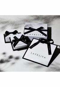 Four rectangular gift boxes in white with black accents and ribbons, featuring the brand "LATELITA" prominently displayed on each.
