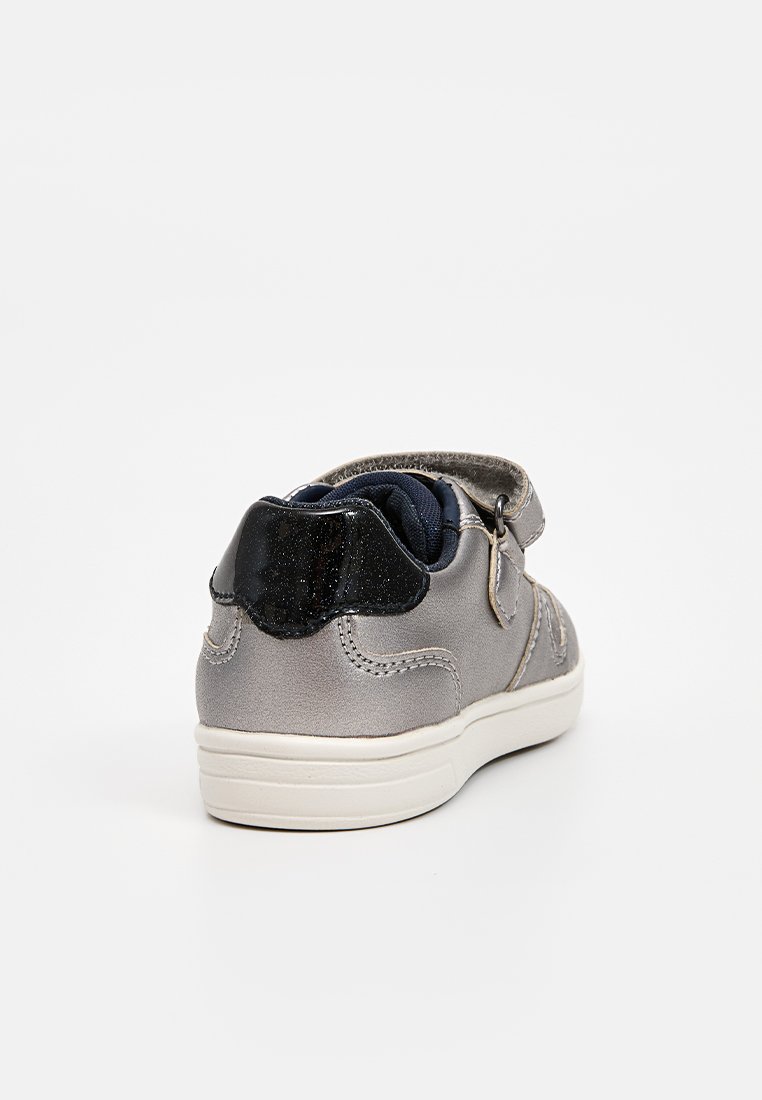 Sneaker in tessuto grigio con un accento sul tallone glitterato nero, suola in gomma bianca e design della punta arrotondata. Cinghia regolabile per una vestibilità facile.