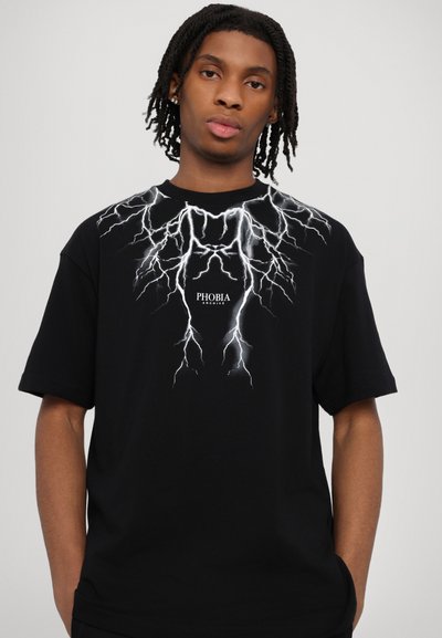 T-shirt nera in cotone con una grafica a forma di fulmine bianco sul petto e il logo "PHOBIA ARCHIVE" al centro, sotto il design.