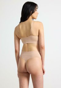 Conjunto de bralette sin costuras y tanga de cintura alta en tono nude. Tejido suave y elástico, diseño minimalista, tirantes ajustables, textura suave.