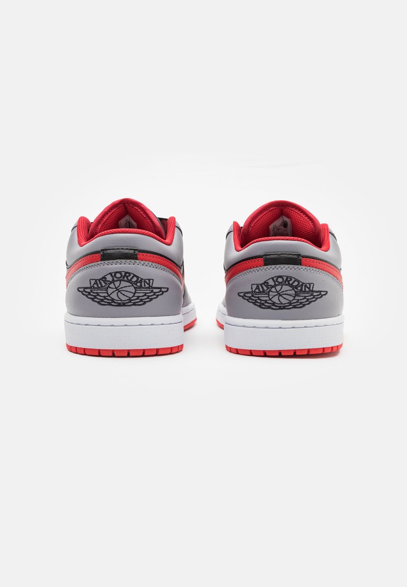 Szare sneakersy z czerwonymi akcentami, z wyściełanym kołnierzem, białą podeszwą i wytłoczonym logo. Gładka faktura z połączenia materiałów.