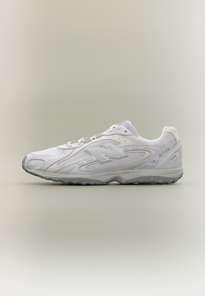 Baskets basses blanches New Balance 2041 avec semelle grise, logo latéral et design texturé sur un fond neutre clair.