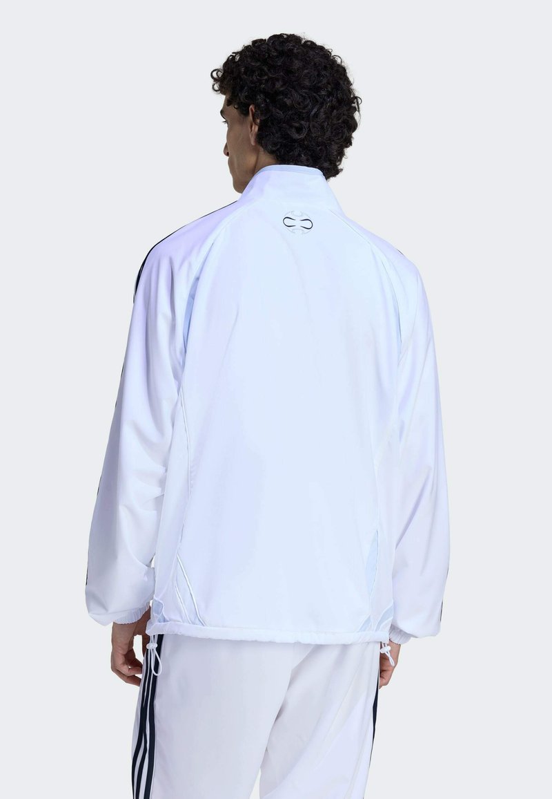 Veste de sport blanche avec un col montant, des poignets élastiques et un ourlet à cordon de serrage. Comprend un logo dans le dos et des détails de coutures contrastantes.