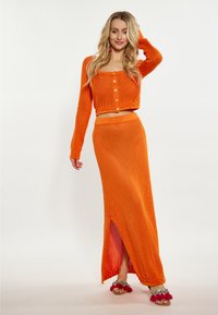 Oranžová háčkovaná pletená dvojdielna súprava obsahujúca skrátený cardigan s gombíkovými zapínaniami a maxi sukňu s bočným rozparkom.