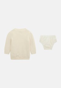 Maglione chiaro a maniche lunghe con scollo tondo, abbinato a un copri pannolino con vita arricciata dello stesso colore, entrambi realizzati in tessuto morbido.