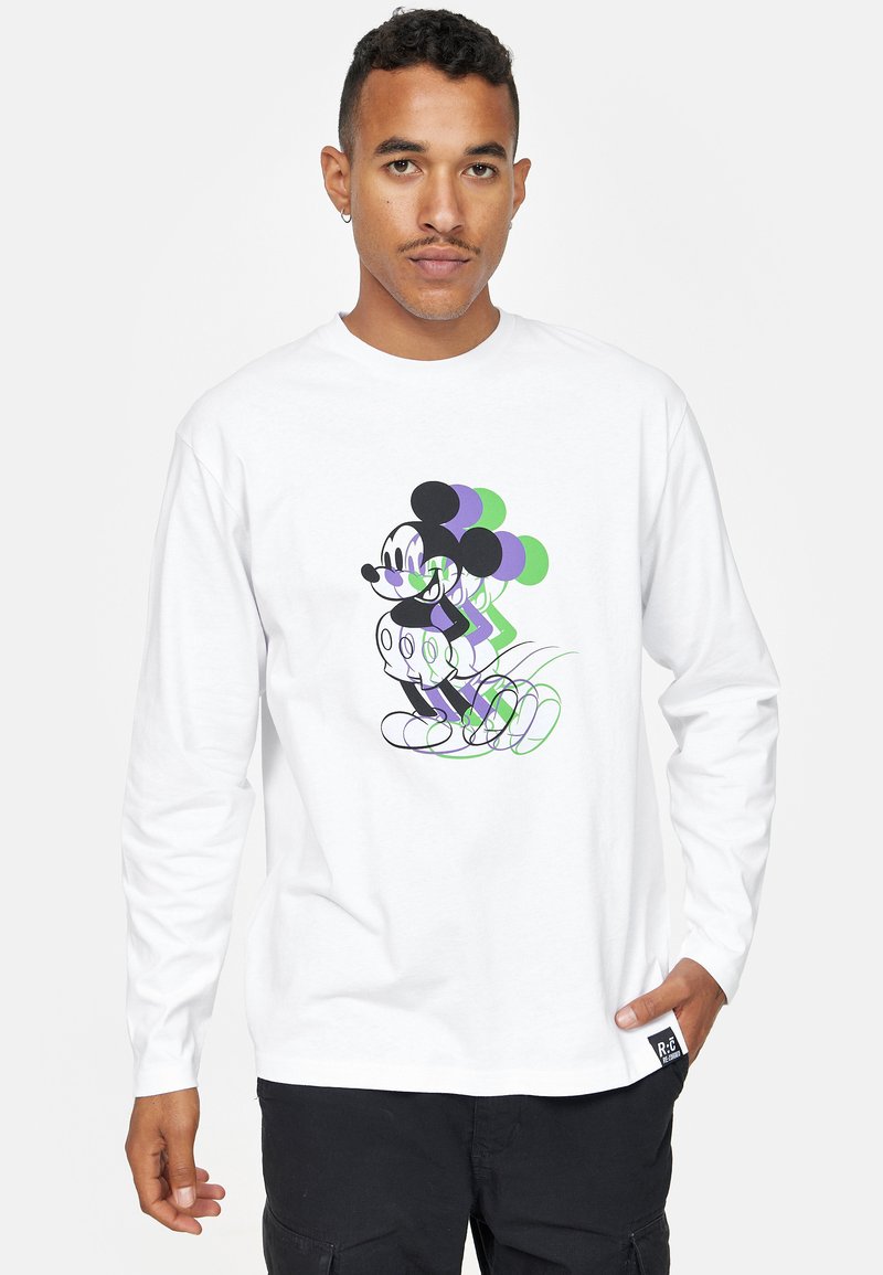 Maglietta a maniche lunghe bianca con grafica di un Mickey Mouse stilizzato in nero, verde e viola su uno sfondo semplice.