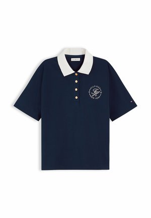 Polo blu navy a maniche corte con colletto bianco, quattro bottoni e logo Tommy Hilfiger con la scritta "Hilfiger New York 1985" sul petto.