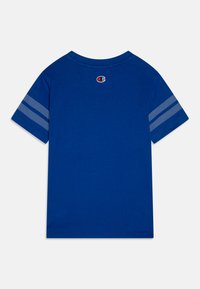 Blaues T-Shirt mit kurzen Ärmeln und rundem Halsausschnitt, das ein Logo auf dem oberen Rücken und zwei horizontale Streifen mit einem Punktmuster auf den Ärmeln aufweist.