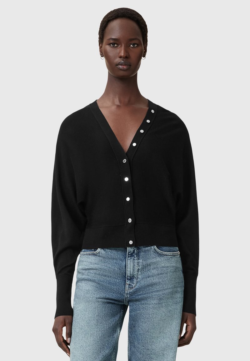 Zwarte gebreide cardigan met een V-hals en knoopsluiting, met een relaxte pasvorm, lange mouwen en contrasterende zilveren knopen.