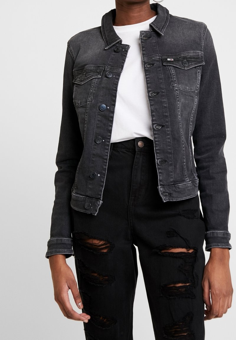 Czarna kurtka z denimu o dopasowanym kroju, z kołnierzem, zapięciem na guziki i przetarciami. W zestawie z czarnymi, podartymi jeansami.