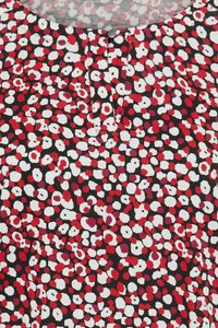 Korte mouw top met een zwarte achtergrond en abstracte stippenpatronen in rood en wit. Ronde halslijn met een detail van een driedelige knopenlijst.