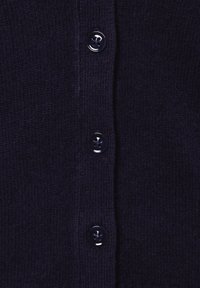 Granatowy sweter z dzianiny z pięcioma okrągłymi, błyszczącymi guzikami z przodu, o miękkiej teksturze i drobnych detalach w tkaninie.