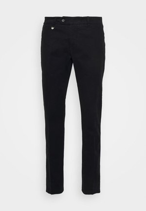 Pantaloni in cotone neri con una vestibilità slim, dotati di chiusura frontale con bottone, passanti per cintura e un piccolo accento metallico vicino alla vita.