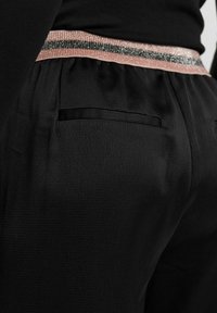 Zwarte broek met een gladde textuur, een enkele achterzak en een decoratieve tailleband met roze en metallic strepen.