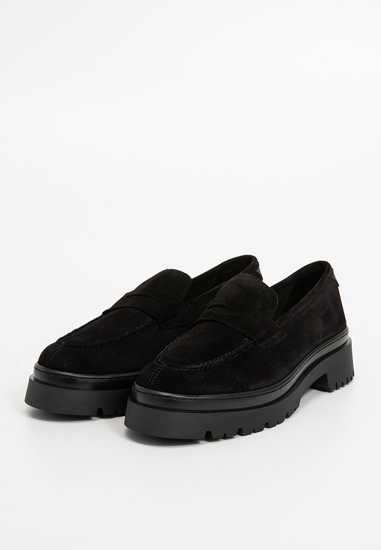 Ein Paar schwarze Wildleder-Loafer mit dicken Gummilaufsohlen, abgerundeten Zehen und einem klassischen Penny-Riemen-Design.