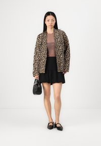 Leopard-print jacket, sheer brown top, black ruffled skirt, black handbag, and slip-on shoes with decorative accents, creating a layered look.