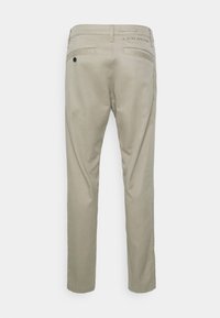 Pantalones de algodón beige de corte recto, con bolsillos traseros y sutiles detalles de marca cerca de la cintura. Textura suave.