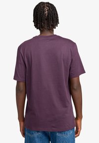 Short-sleeve t-shirt in dark purple cotton fabric, featuring a crew neck and relaxed fit, viewed from the back with plain design.