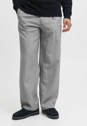 Pantaloni gri deschis, comozi, cu un design ajustat, având pliseuri și buzunare laterale, asortați cu pantofi negri.