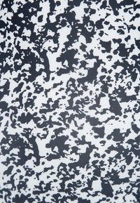 Abstrakt svart och vitt tyg med ett splattermönster med varierande former och texturer, som skapar ett dynamiskt, modernt utseende.