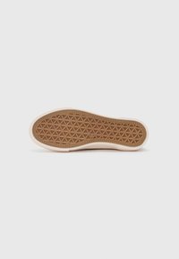 Rubber shoe sole with a textured honeycomb pattern in brown. Rounded edges in a light beige color. Smooth upper edge with subtle stitching detail.
