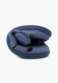 Modrá látková bota s měkkou, flexibilní podešví, má texturovaný svršek a otevřený design se suchým zipem pro snadné obouvání.
