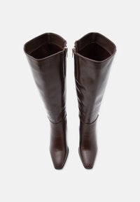 Hnědé kožené vysoké boty s čtveratými špičkami, bočními zipy a hladkým povrchem. Vnitřek má hladký povrch.