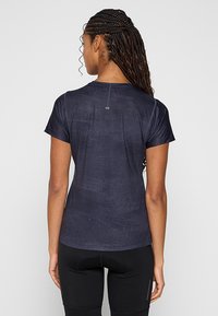 Granatowa koszulka sportowa z materiału odprowadzającego wilgoć, krótki rękaw i dopasowany krój. Posiada subtelną teksturę oraz odblaskowy detal logo.