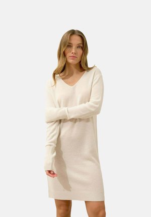 Abito maglione a V in crema, con polsini e orlo a costine, texture morbida e vestibilità rilassata che termina sopra il ginocchio.