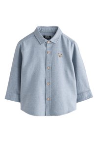 Camicia azzurro chiaro a maniche lunghe con bottoni, realizzata in tessuto intrecciato, con bottoni in legno e un piccolo ricamo di un orso sul petto.