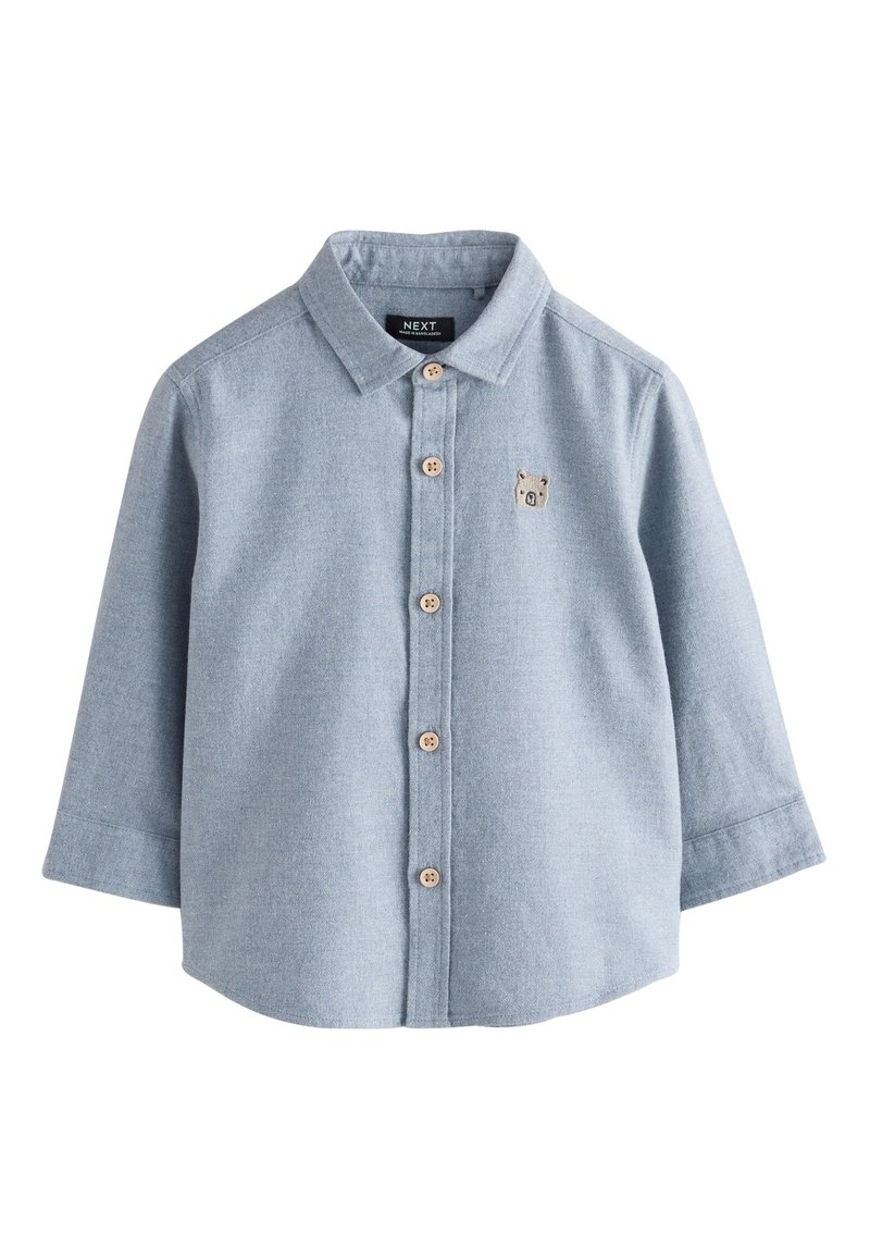 Camicia azzurro chiaro a maniche lunghe con bottoni, realizzata in tessuto intrecciato, con bottoni in legno e un piccolo ricamo di un orso sul petto.
