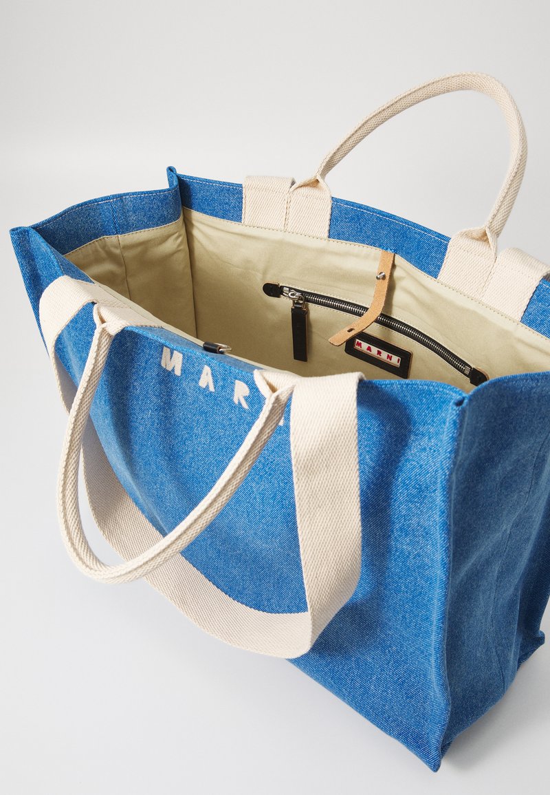 Sac fourre-tout en denim bleu avec poignées crème, intérieur beige, poche zippée, et logo "MARNI" sur l'étiquette intérieure et le bord extérieur.
