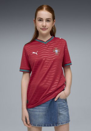 Maglia da calcio rossa con motivo a strisce orizzontali, maniche corte e accenti turchesi. Presenta uno stemma e un logo Puma sul petto.